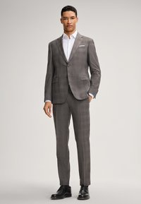 Grau kariertes Anzug mit einer taillierten Passform, bestehend aus einem knöpfbaren Blazer, passenden Hosen und einem weißen Hemd, ergänzt durch schwarze Lederschuhe.