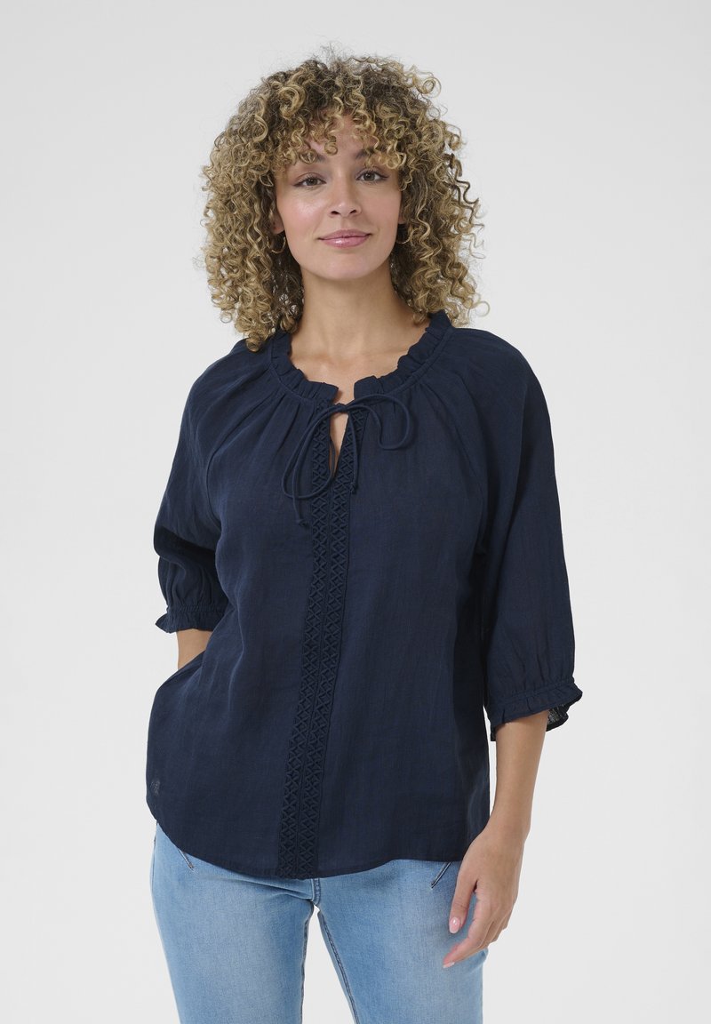Navy blue linen blouse featuring a round neckline with a tie, three-quarter puff sleeves, and a decorative vertical lace trim.