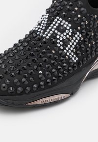 Schwarze Sneaker, verziert mit facettierten schwarzen und klaren Strasssteinen, mit einem eleganten Design und einem metallischen Karl Lagerfeld Akzent.