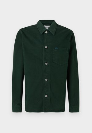 Donkergroen katoenen overhemd met knopen, voorzien van een borstzak, zilveren knopen en een gestructureerde afwerking. Lacoste-logo op de zak.