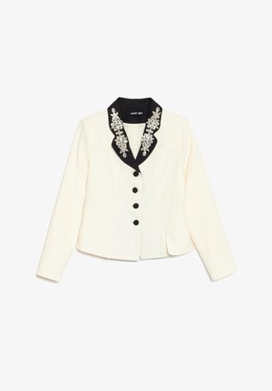 Blazer crème avec col noir orné d'embellissements floraux en cristal et quatre boutons noirs sur le devant, manches longues, coupe cintrée.
