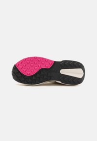 Black and pink rubber sneaker sole with a textured grip pattern and logo. The pink section is round, while the black has triangular spikes.