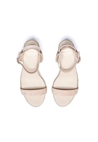 Sandales en suède beige avec deux larges brides et une bride à la cheville, dotées d'une semelle plate de style espadrille et d'une texture lisse et mate.