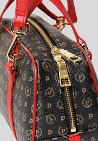 Borsa nera strutturata con accessori dorati, manici in pelle rossa e motivo con logo. Presenta una zip prominente lungo la parte superiore.