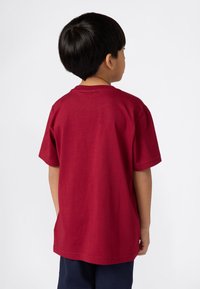 Rød bomulls t-skjorte med korte ermer og rund hals, sett fra baksiden. Stoffet er glatt uten synlige mønstre eller detaljer.