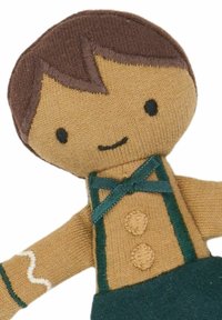 Textielpop met bruin garenhaar, een beige gezicht, groene bretels en een blauwe broek. Naaiwerkdetails omvatten knopen en een witte accenten op de arm.