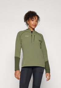 Olīvu zaļa rāvējslēdzēja pulovers ar teksturētu audumu, pieguļošs dizains un garas piedurknes. Iezīmēts ar krūšu kabatu un logo augšējā kreisajā pusē.