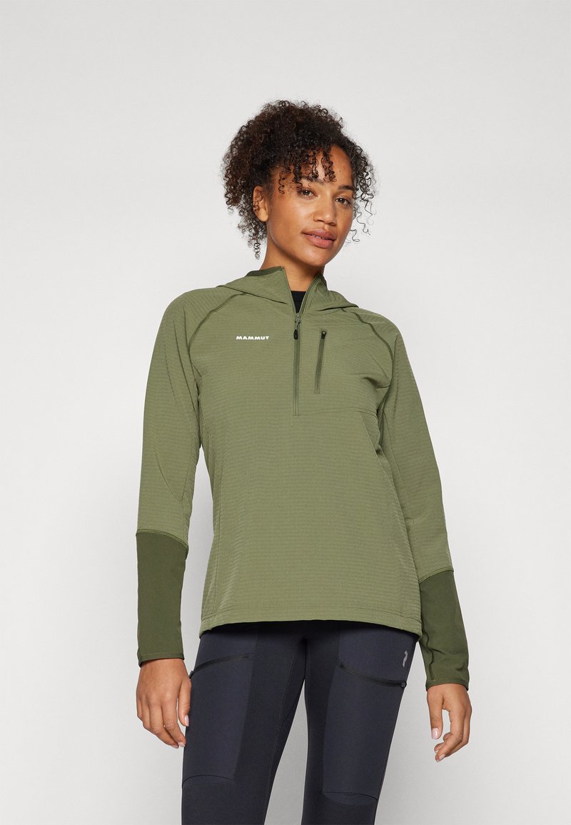 Olīvu zaļa rāvējslēdzēja pulovers ar teksturētu audumu, pieguļošs dizains un garas piedurknes. Iezīmēts ar krūšu kabatu un logo augšējā kreisajā pusē.