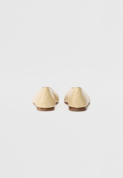 Balerini din piele bej cu vârful rotund și talpă moale, plată. Au un design fără cusături și detalii minime pe spate.