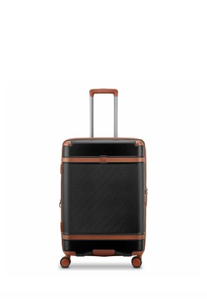 Valigia rigida nera con finiture in pelle marrone, quattro ruote girevoli e manico retrattile esteso.