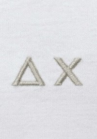 Tessuto bianco con ricamo argento della lettera greca delta (Δ) e della lettera X (X) con un finish texture.