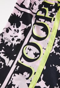 Material textil cu imprimeu floral în culori negre și roz, cu un accent galben strălucitor și cuvântul "JOOP!" integrat în design.