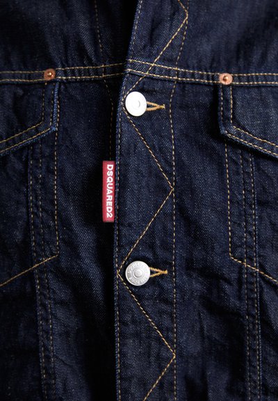 Czarna kurtka dżinsowa z widocznymi szwami, metalowymi guzikami i czerwoną metką z napisem "DSQUARED2". Detaliczne szwy podkreślają wzór.