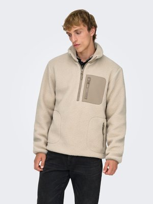 Fleece trui in licht beige met een hoge kraag, borstzak en zijritszak. Gestructureerde, zachte stof met gladde contrasterende accenten.