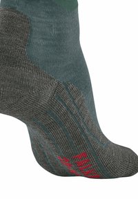 Calcetín gris y verde con un tejido texturizado, rayas horizontales, talón reforzado y un acento rojo en la punta.