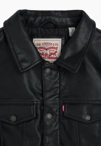 Black leather jacket featuring a classic collar, branded tag, and snap button closures on chest pockets with red Levi's accent.