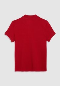 Polo rouge à manches courtes vu de dos, avec un col côtelé et un design uni sur un fond neutre.