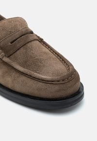 Braune Wildleder-Lederslipper mit strukturiertem Obermaterial, schwarzer Gummisohle und dekorativer Naht. Verfügt über eine glatte Oberfläche und keinen sichtbaren Beschlag.