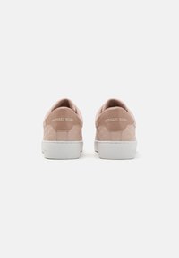 Sneaker rosa chiaro con un design testurizzato, dettagli lisci e una suola bianca. Presenta il logo "Michael Kors" sul retro.