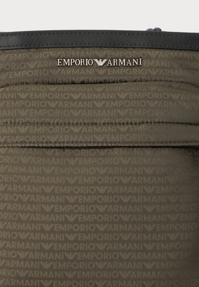 Borsa in nylon verde scuro con logo "Emporio Armani" impresso, caratterizzata da una finitura in pelle nera e una texture liscia.