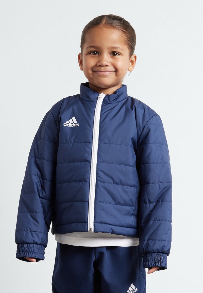 Dunkelblaues Puffer-Jacke mit weißem Reißverschluss und adidas-Logo, ausgestattet mit einem Stehkragen und elastischen Bündchen, durchgehend mit gesteppter Textur.