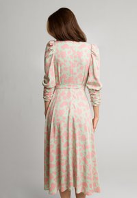 Kwiatowa sukienka z bufkami, w pastelowo-zielonej bazie i różowym wzorze kwiatowym. Lekka tkanina, marszczone detale przy rękawach.