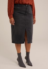Falda lápiz de mezclilla en gris oscuro con una abertura frontal, complementada con botines en gris. Presenta una cintura clásica y una silueta ajustada.