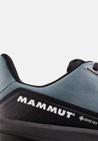Κοντινό πλάνο γκρι και μαύρου παπουτσιού Mammut με ετικέτα Gore-Tex, που δείχνει το επάνω ύφασμα και μέρος της σόλας.