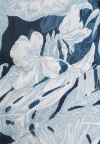 Tecido floral com grandes flores brancas e folhas azul-escuras. O design tem uma aparência texturizada e linhas intrincadas em várias tonalidades de azul.