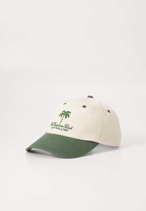 Beige caps med grønn skygge, med et brodert palmetre og teksten "On Vacation Club LET'S TAKE A TRIP" i grønt. Laget av bomull.