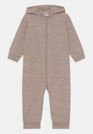 Kapsový overal v světle béžové barvě, vyrobený z měkké, strukturované látky. Obsahuje zip po celé délce a žebrované manžety na rukávech a kotnících.