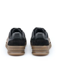 Czarne skórzane i zamszowe sneakersy z gumową podeszwą. Posiadają wyściełany kołnierz oraz teksturowane akcenty po bokach. Model typu mid-top.