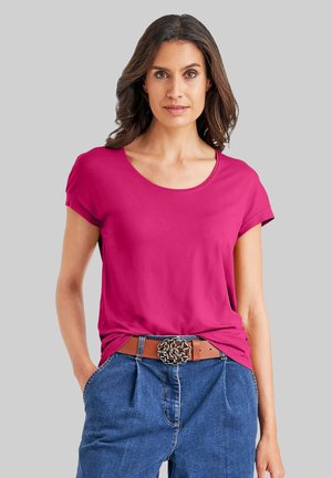 Fuchsia T-shirt met korte mouwen en een ronde halslijn, gecombineerd met blauwe high-waisted jeans en een bruine riem met een decoratieve gesp.