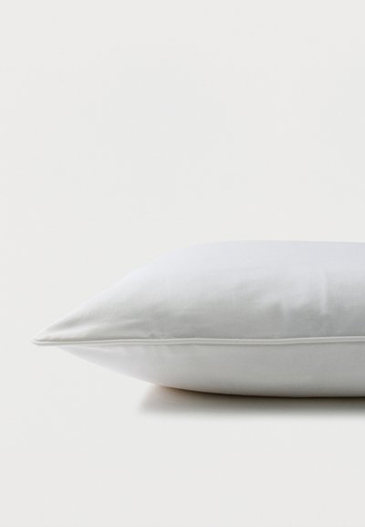 Λευκό ορθογώνιο μαξιλάρι με λείο ύφασμα, ακουμπισμένο σε επίπεδη επιφάνεια με φόντο ένα απλό λευκό τοίχο.