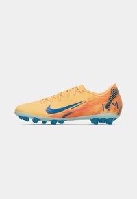 Nike futbola futbolboti ar spilgtu dzeltenoranžu virspusi, ziliem akcentiem un teksturētu rakstu. Iespējas viegls dizains un punktveida zole.