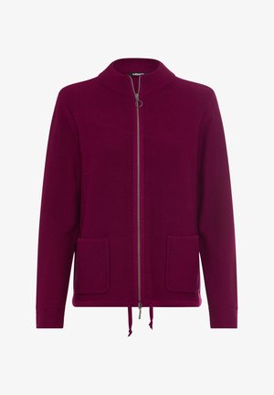 Cardigan in deep burgundy, knitted texture, front zipper closure, two patch pockets, and drawstring hem. Minimalist design with a high collar.