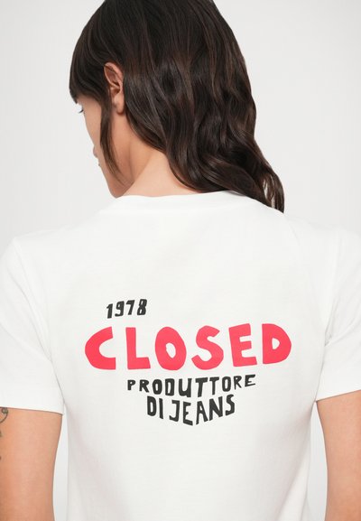 Biele bavlnené tričko s výrazným červeným a čiernym textom na chrbte: "1978 CLOSED PRODUTTORE DI JEANS" v kombinovanom štýle písma.