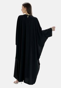Schwarzes Cape-Kleid mit fließendem Design, langen Ärmeln und einem Schlüsselloch-Detail im Rücken. Hergestellt aus leichtem Stoff mit glatter Textur.