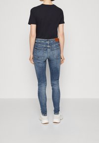 Smal höga jeans i blekt blå denim med en ljus tvätt, med bakfickor och läderetikett vid midjan. Matchas med vita sneakers.