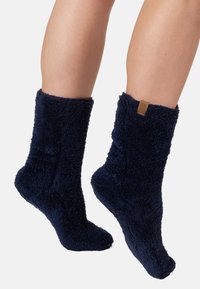 Sötétkék fleece zoknik, soft, struktúrált designnal és rövid szegéllyel; az oldalon egy kis barna márkajelzés található.