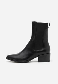 Černá kožená kotníková bota s elastickými bočními panely, špičatou špičkou a blokovým podpatkem. Hladká textura s minimálními kovovými prvky a elegantním designem.