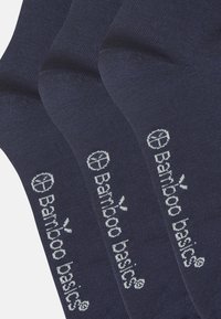 Chaussettes en bambou de couleur bleu marine profond avec une texture lisse. Présente un logo imprimé en blanc "Bamboo basics" sur le côté.
