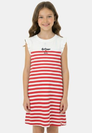 Fille souriante aux cheveux bruns ondulés portant une robe blanche sans manches à rayures horizontales rouges avec le texte « Lee Cooper London ».