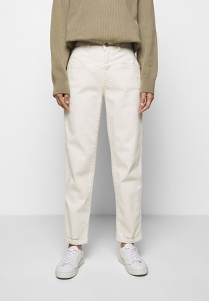Jean droit en coton blanc avec une taille haute. Associé à un pull en tricot beige et des baskets blanches, comportant un logo de marque visible à l'ourlet.