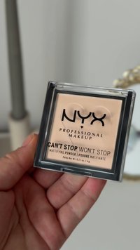 Polvere opacizzante NYX Can't Stop Won't Stop in un compatto quadrato trasparente. Polvere beige chiaro con scritte nere su un coperchio trasparente.