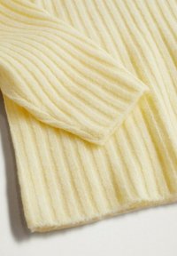 Maglione a coste in morbido tessuto giallo, con righe verticali e una texture accogliente, dotato di un dettaglio con polsini piegati.