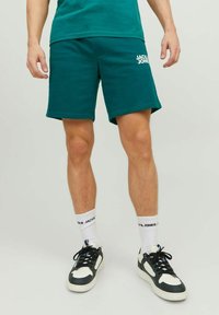 Teal cotton shorts with an elastic waistband and side pockets; features a white "JACK & JONES" logo on the left leg.