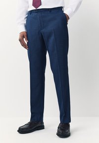 Marineblaue maßgeschneiderte Hosen mit strukturiertem Finish, flachem Bund, Seitentaschen und kombiniert mit glänzenden braunen Mokassins.