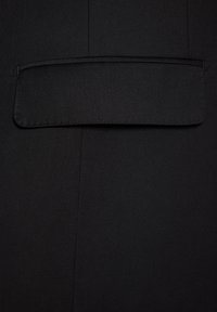 Czarna tkanina o gładkiej teksturze; posiada jedną kieszeń z listwą, czyste linie i brak widocznych zapięć lub wzorów.