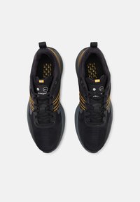 Ett par svarta sportskor med orangea ränder och Nike-logotyper, sedda ovanifrån på en helt vit bakgrund.